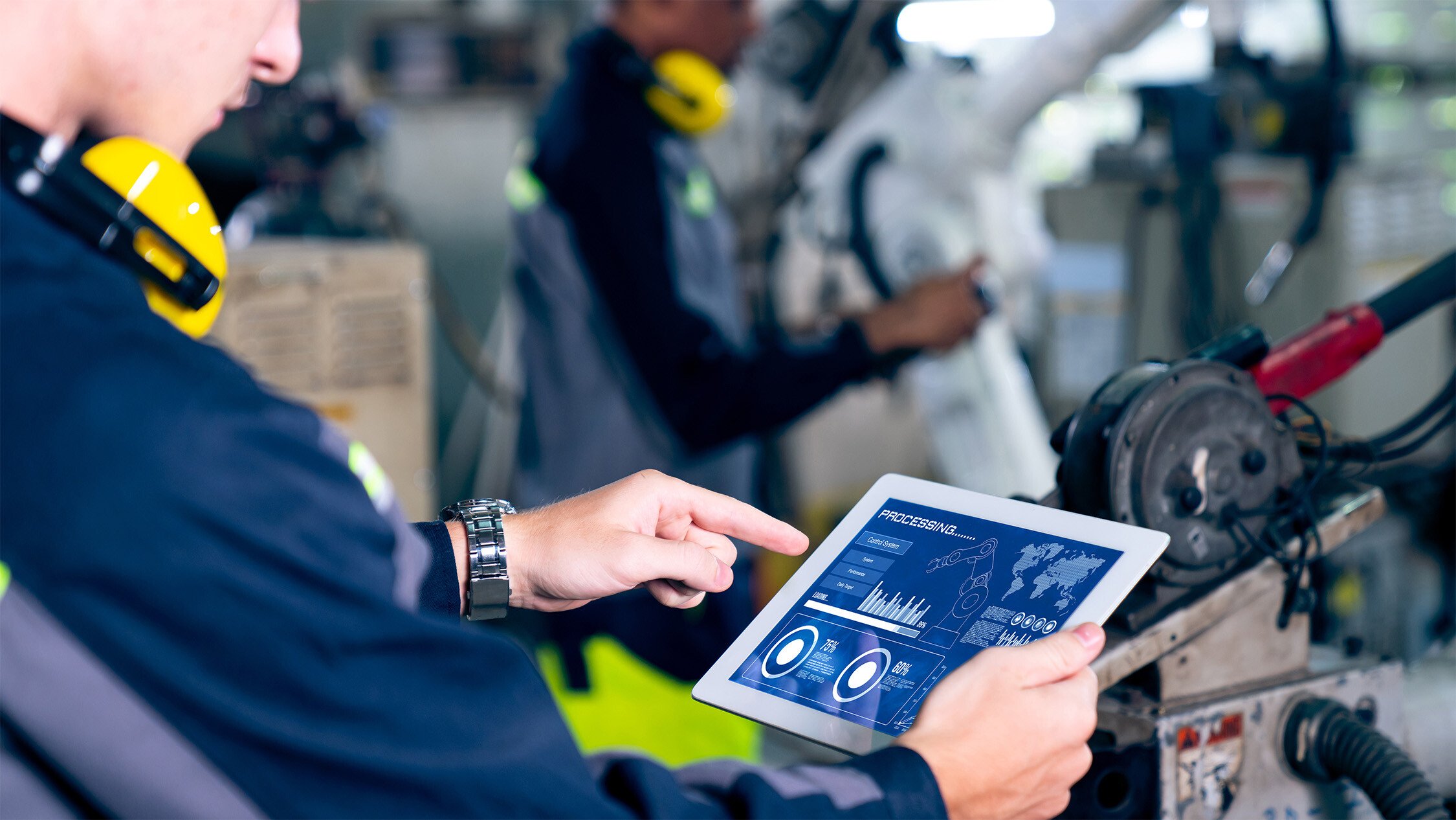 manufacturing worker examining a tablet to maintain a manufacturing machine