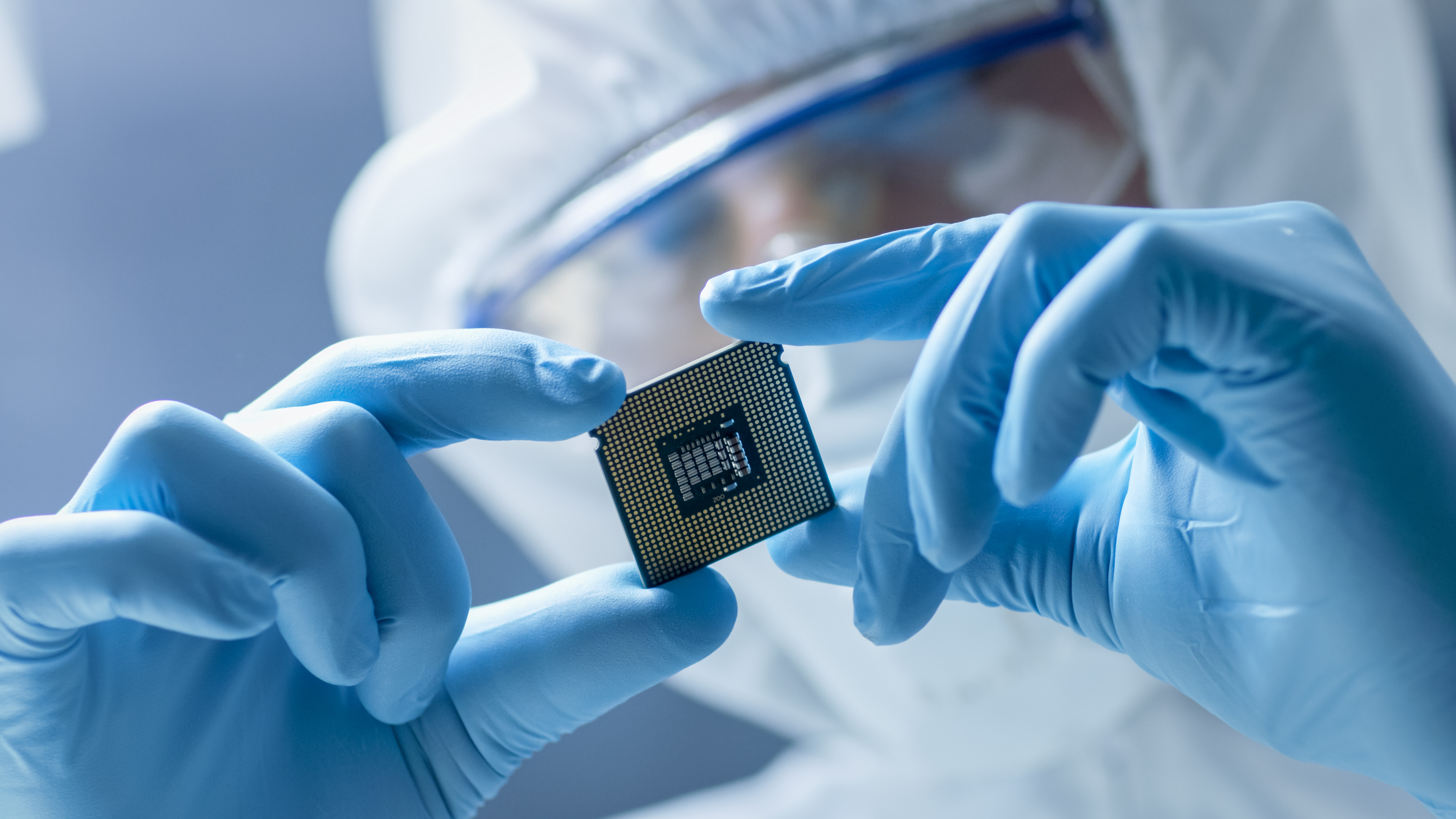 semiconductor worker with blue gloves examining microchip