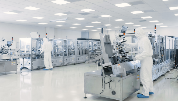 Technicians in cleanroom suits operating machinery in sterile semiconductor manufacturing environment