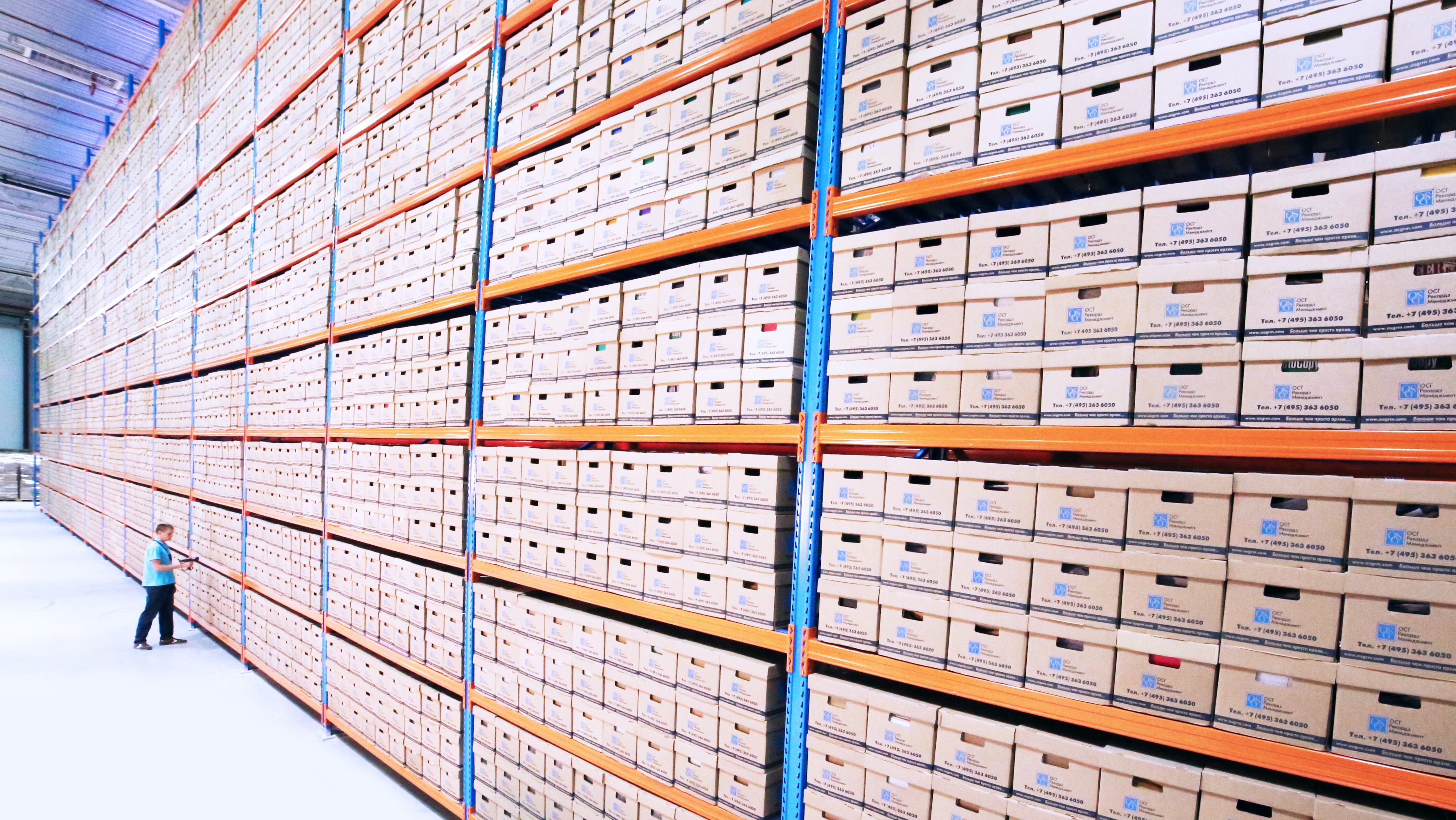 huge row of shelves with one warehouse worker scanning an item